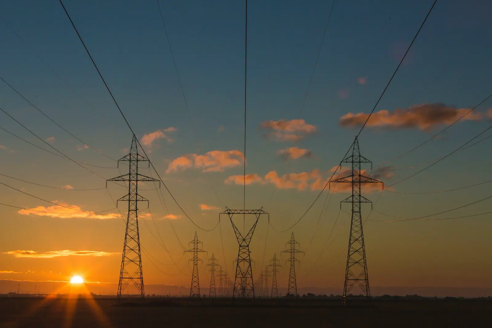 High-voltage lines at dusk — the grid a home battery still sits on